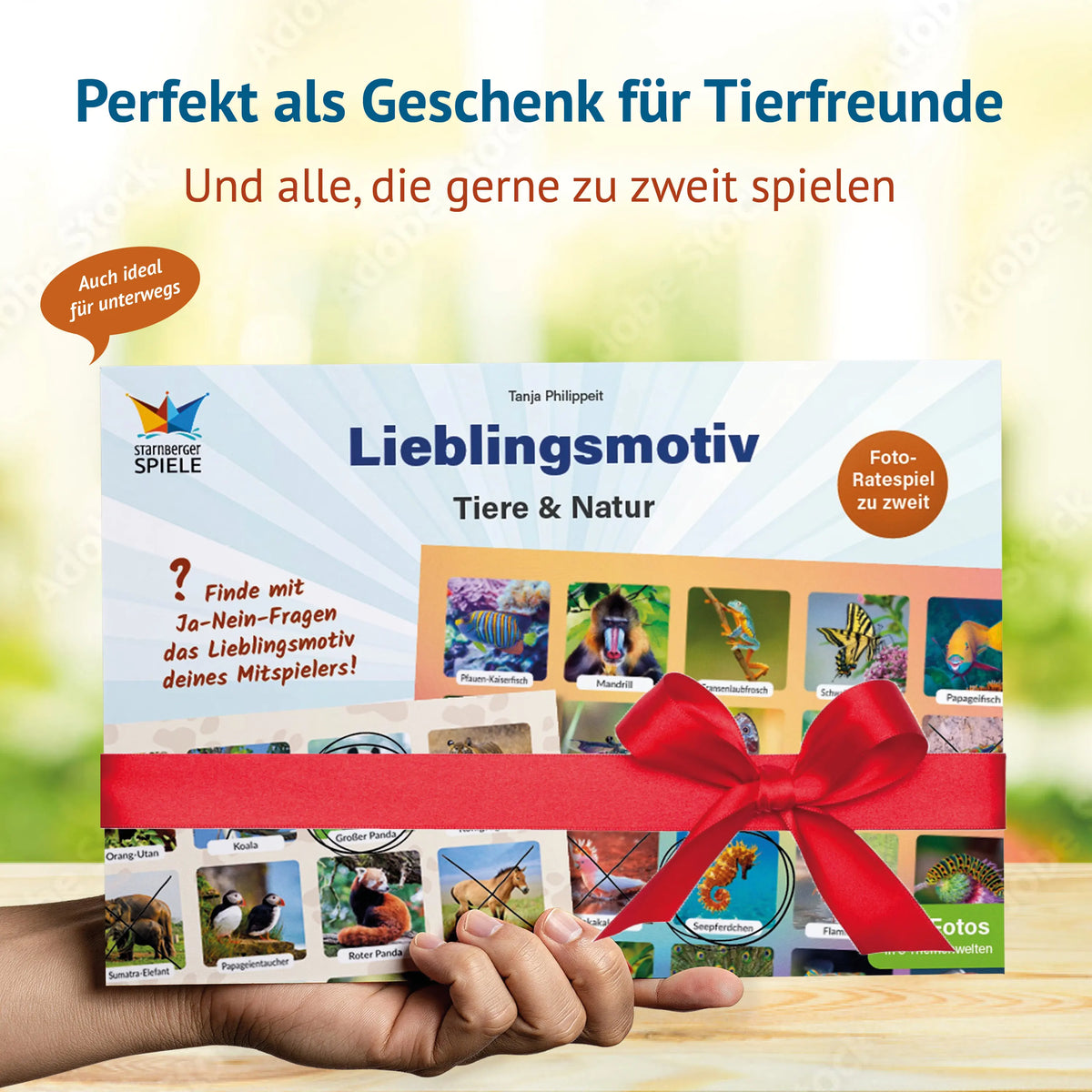Hand hält den Spielblock „Lieblingsmotiv – Tiere & Natur“ mit roter Geschenkschleife. Text: Perfekt als Geschenk für Tierfreunde und alle, die gerne zu zweit spielen – auch ideal für unterwegs.