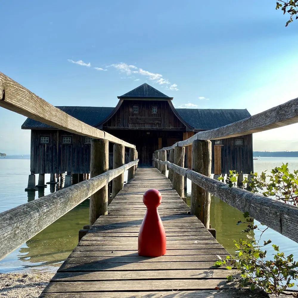 Ms. Meeple auf dem Holzsteg zum historischen Bootshaus in Stegen am Ammersee